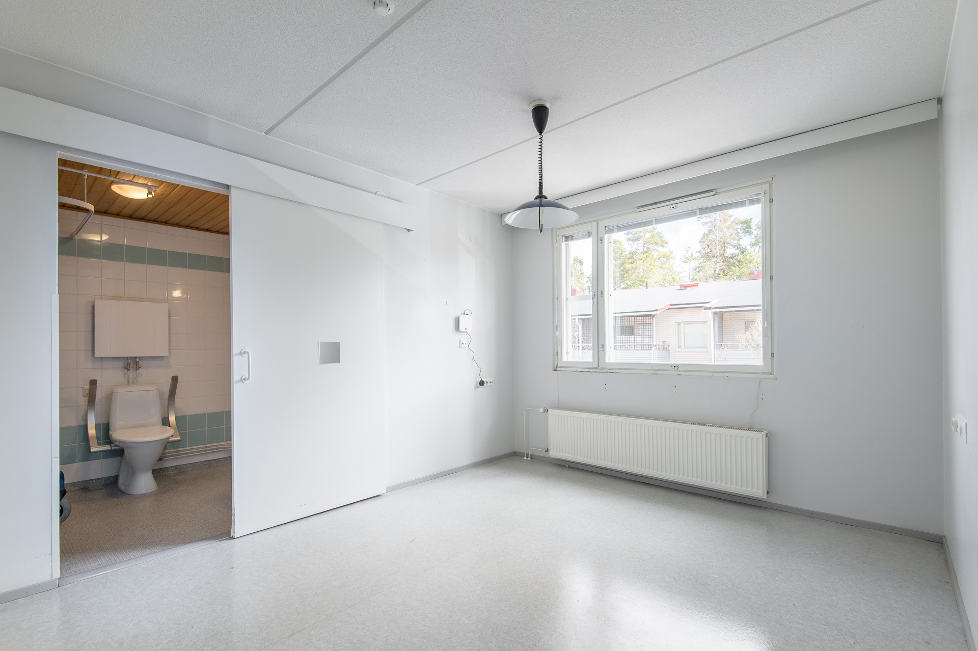 Ett tomt rum med foenster och doerr till badrum